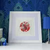 Honey Bee Red Spot Lino Print Framed in White on a Chest of Drawers in front of Peacock Feather Paper