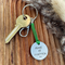 1 inch aluminium disc hand stamped with the words make it happen in capital letters with a small arrow stamp below.  shown on a green cord turning the disc into a hanging keyring