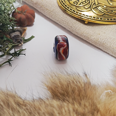 A photo of the bead on a white background but slightly framed with items associated with the viking era