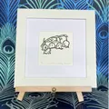 Lily of the Valley framed in white on a beech easel against a peacock background