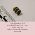 Museam photo of the find showing the barrel like bead with raised yellow lines