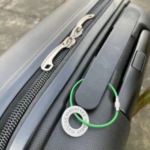 1 inch aluminium washer stamped with the words busy making memories.  the washer has been threaded onto a green coloured wire to make a luggage tag.  it is shown attached to the handle of a suitcase