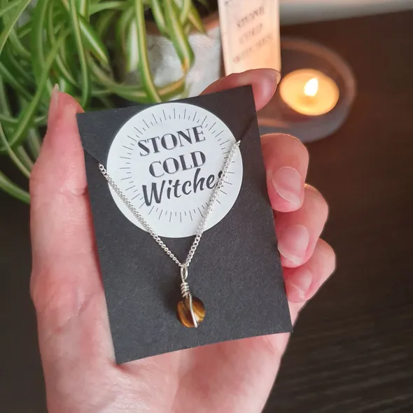 Small tigers eye sphere bound in a simple wire wrap onto dainty silver chain. Crystal is brown, gold and bronze