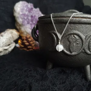 Small moonstone sphere bound in a simple wire wrap onto silver chain. Moonstone is a bright white with delicate flashes of blue, opaque is some areas and translucent in others