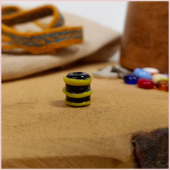 Subbersund Wasp Bead. A black bead with three raised lines of yellow photo taken showing the bead stood on its end