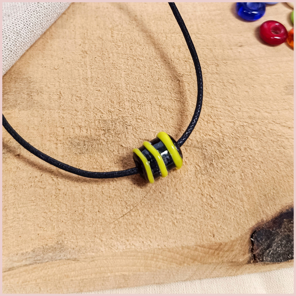 Subbersund Wasp Bead. A black bead with three raised lines of yellow shown on a cord