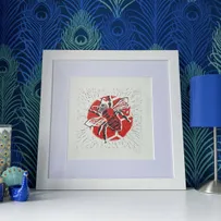 Honey Bee Red Spot Lino Print Framed in White on a Chest of Drawers in front of Peacock Feather Paper
