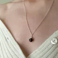 Small black onyx sphere bound in a simple wire wrap onto silver chain