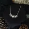Silver colour moon phase necklace with a full moon in the middle and 2 crescent moons either side, decreasing in size. The pendant has a shiny yet textured appearance and hangs on a silver plated chain about collerbone length