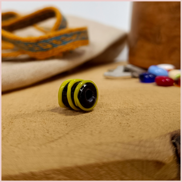 Subbersund Wasp Bead. A black bead with three raised lines of yellow photo taken from the side
