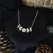 Silver colour moon phase necklace with a full moon in the middle and 2 crescent moons either side, decreasing in size. The pendant has a shiny yet textured appearance and hangs on a silver plated chain about collerbone length