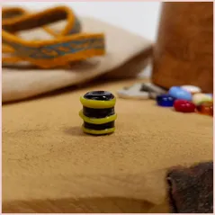 Subbersund Wasp Bead. A black bead with three raised lines of yellow photo taken showing the bead stood on its end