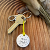 1 inch aluminium disc hand stamped with the words shine bright in lower case lettering, surrounded by small stars.  Shown attached to a yellow cord turning the disc into a hanging keyring