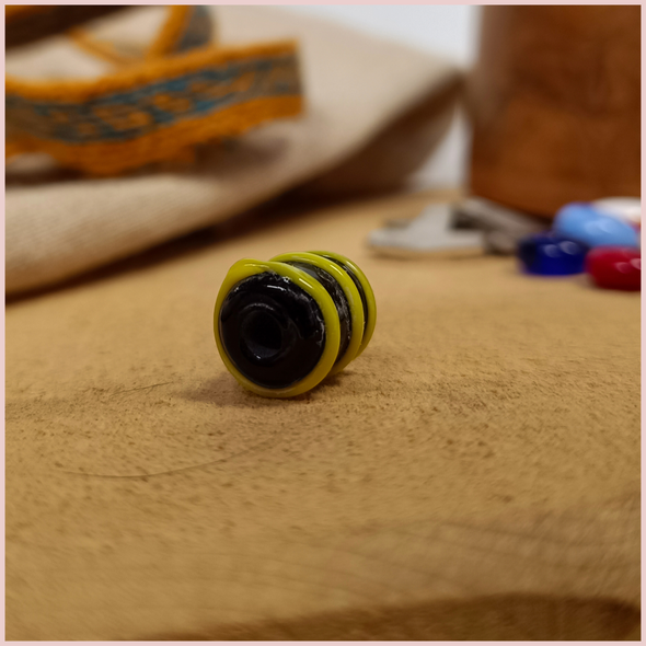 Subbersund Wasp Bead. A black bead with three raised lines of yellow photo taken end on with the hole visible
