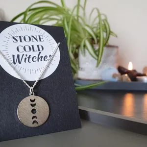 Silver chain necklace with circular silver coloured pendant with vertical moon phase cut out