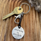 1 inch aluminium disc hand stamped with the words anything is possible in lowercase font.  There is a moon and stars design at the top and mountains below.  shown on a black cord turning the disc into a hanging keyring