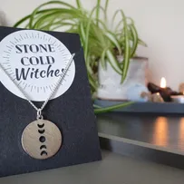 Silver chain necklace with circular silver coloured pendant with vertical moon phase cut out