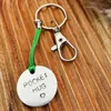 1 inch aluminium circular disc hand stamped with the words pocket hug in capital letters with a small heart below.  shown on a green coloured cord to make it into a hanging keyring