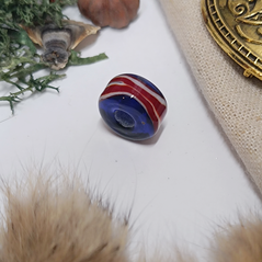 A photo of the bead on a white background but slightly framed with items associated with the viking era
