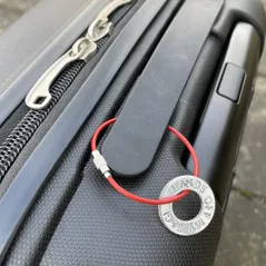 hands off my  bag luggage tag, hands off my bag in capital letters hand stamped onto 2.5cm aluminium washer, threaded onto a sturdy red wire and attached to the handle of a suitcase
