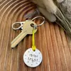 1 inch aluminium disc hand stamped with the words shine bright in lower case lettering, surrounded by small stars.  Shown attached to a yellow cord turning the disc into a hanging keyring