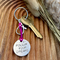 1 inch aluminium disc hand stamped with the words follow your dreams in capital letters, with small moon and stars design above.  Shown on a deep pink cord to turn the disc into a hanging keyring