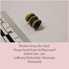 Museam photo of the find showing the barrel like bead with raised yellow lines