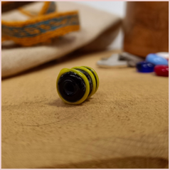Subbersund Wasp Bead. A black bead with three raised lines of yellow photo taken end on with the hole visible