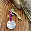 1 inch aluminium disc hand stamped with the words follow your dreams in capital letters, with small moon and stars design above.  Shown on a deep pink cord to turn the disc into a hanging keyring