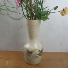 Handmade wheel-thrown stoneware vase with textured slip design, shown on a wooden table with fresh flowers.